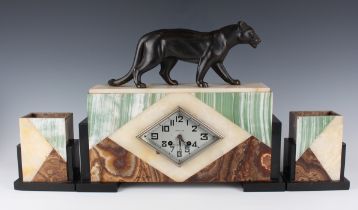 An Art Deco French varicoloured onyx, slate and spelter mantel clock garniture, the clock with eight