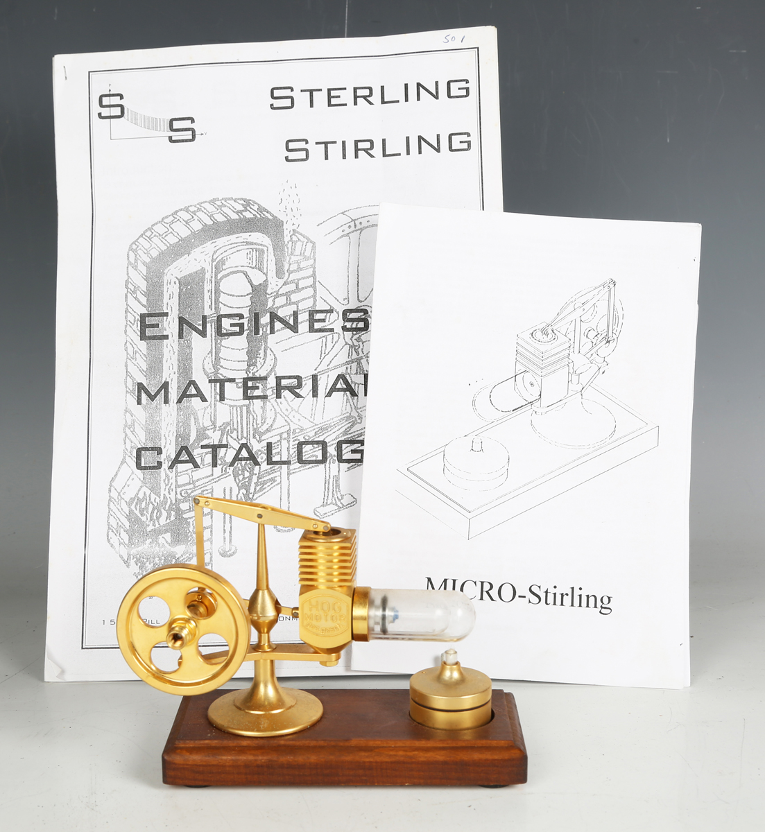 A Micro-Stirling miniature 'Hog Motor' hot air engine with balance beam and glass cylinder, heated