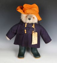 A Gabrielle Designs Paddington Bear wearing an orange hat, blue duffel coat and green Dunlop