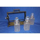 A silver plated tantalus supporting three cut glass decanters (one af)