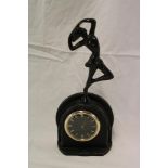 An Art Deco mantel clock with circular dial in painted metal arched case surmounted by a female