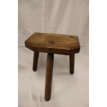 An old elm rectangular three-legged stool,