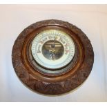 A small aneroid barometer in carved walnut circular case