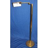 A vintage brass articulated floor reading lamp with adjustable arm on circular base