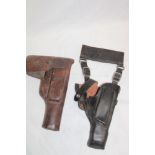 A brown leather pistol holster with attached magazine section and one other black leather revolver