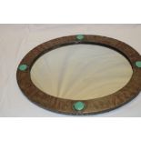 An unusual oval wall mirror in beaten copper oval frame inset with four turquoise porcelain