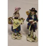 A pair of Samson porcelain figures of a male and female carrying baskets of flowers on floral bases