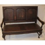 A George III oak settle with triple panelled back and polished seat on cabriole legs,