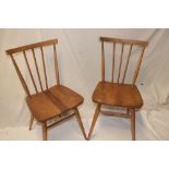 A set of four 1960's Ercol light elm dining chairs with spindle-backs and shaped seats on turned