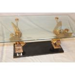 An unusual rectangular coffee table with gilt winged bird supports and bevelled glass top