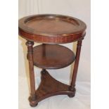 A 19th century mahogany circular three-tier display stand with inset circular recess above