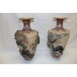 A pair of Japanese satsuma pottery tapered vases decorated in relief with bears, flowers and birds,