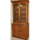 A 19th century polished pine bookcase with cupboard enclosed by two panelled doors,