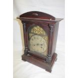 A German bracket-style mantel clock with silvered and gilt arched dial in stained wood rectangular