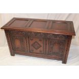 A 1930's carved oak rectangular coffer with triple panelled front and hinged lid,