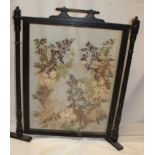 An old ebonised rectangular fire screen with central glass panel inset with a dried flower and