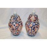 A pair of 19th century Japanese Imari pottery tapered vases and covers with painted figure and