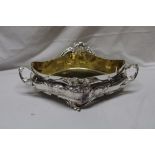 A Continental silvered/white metal oval two handled ornamental bowl with raised scroll decoration,
