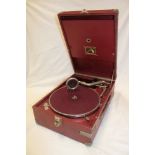 An old portable gramophone by His Master's Voice in red fibre case