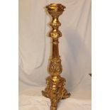 A modern gilt ornamental torchere with tapered column and trefoil base