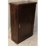 An early 19th century oak wall cupboard with shelves enclosed by a single panelled door,