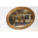 A bevelled oval wall mirror in embossed metal oval frame,