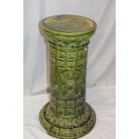 A 19th century green glazed pottery cylindrical jardiniere stand with raised floral decoration,