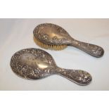 An Edward VII silver hand mirror with raised floral decoration and matching hairbrush,
