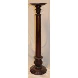 A polished mahogany torchere with tapered column and circular base
