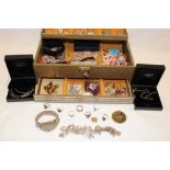 A jewellery box containing a selection of costume jewellery including brooches, necklaces,