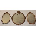 A modern brass framed oval wall mirror with floral decoration,