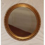 An old oval wall mirror in gilt relief decorated frame,