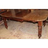A large Victorian oak rectangular extending dining table with two additional central leaves on