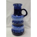 A large West German pottery cylindrical single handed vase with blue glazed decoration,
