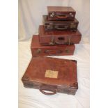 Five various old leather rectangular suitcases in varying sizes and ages