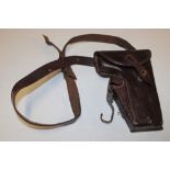 An old brown leather military holster with attached magazine pouch and strap