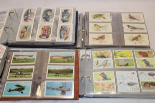 Four albums containing a large selection of various trade cards, tea cards,