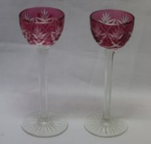 A pair of cranberry tinted cut-glass liqueur goblets with tapered stems and circular bases