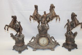 A bronzed spelter mantel clock in the form of a gladiator with horses flanked by a pair of