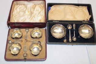 A set of four silver shaped-circular salts together with spoons,