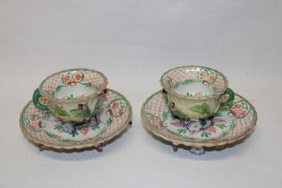 A pair of 19th century china cabinet cups and saucers with raised and painted floral and leaf