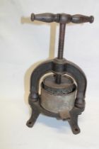 An old cast-iron screw-thread food press with turned wood handle 12" high