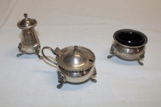 A sterling silver three-piece cruet set comprising lidded mustard pot,