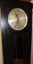A 1930s Art Deco ebonised grandfather-style clock by Enfield with silvered circular dial and