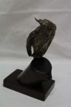 An unusual plated copper inkwell in the form of a parrot with hinged head and glass eyes mounted on