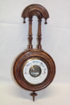 A good quality aneroid barometer with part visible movement in carved walnut case