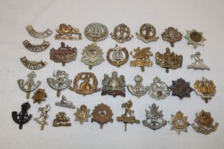 A selection of approximately 30 various military cap badges and insignia including the Cheshire