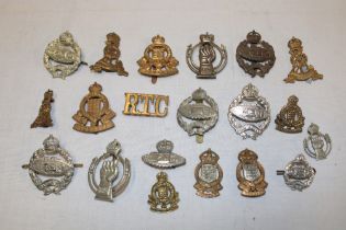 A selection of various military cap badges including Royal Tank Regiment and collars,