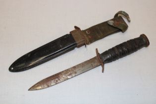 A Second War United States M8 combat knife with single edged blade and leather hilt in composition