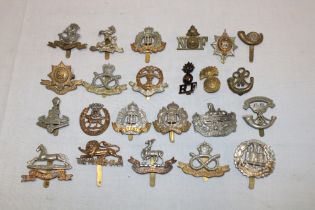 A selection of approximately 22 various military cap badges and insignia including the King's Own,